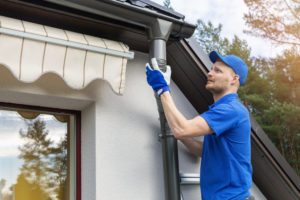 man installing gutter system roofing companies maintain roof